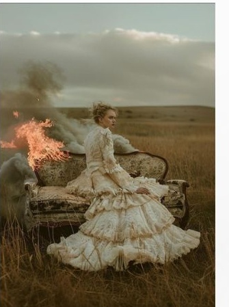 Woman on a burning sofa in a field