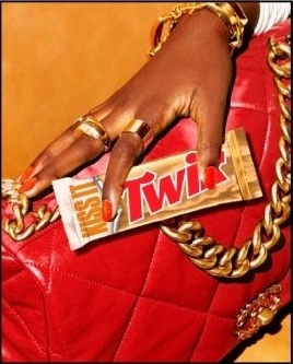 Hand holding a Twix bar over a red bag