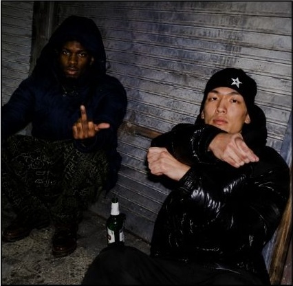 Two people sitting against a shutter at night